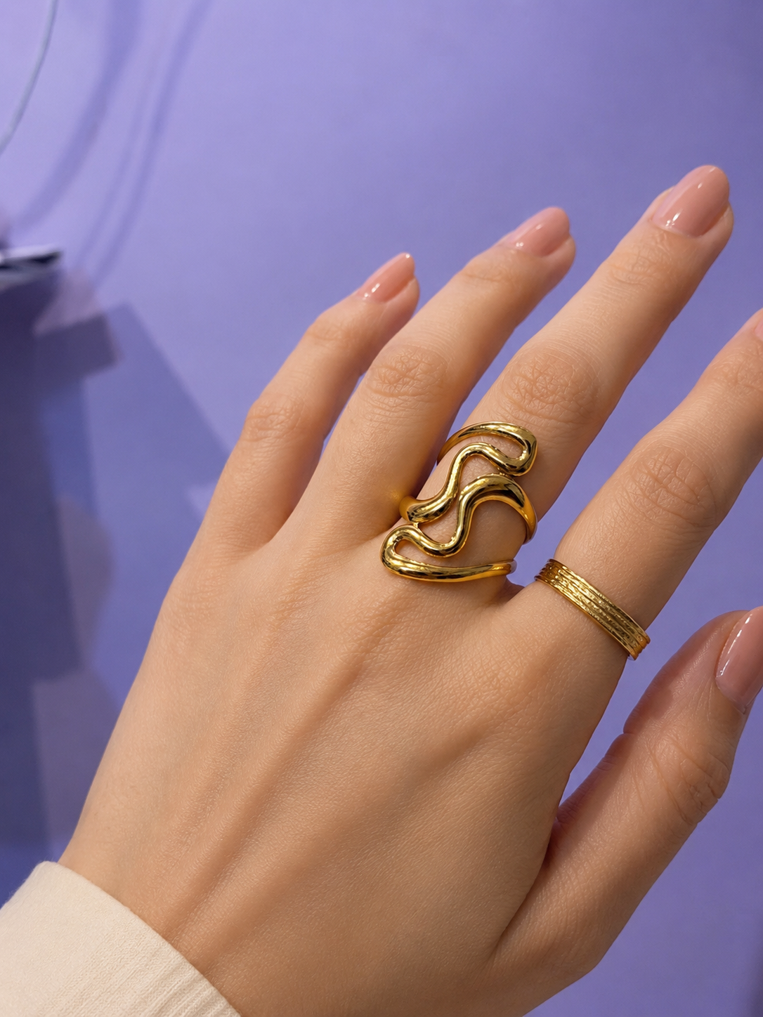Gold-tone wavy open ring on hand, styled with a slim band