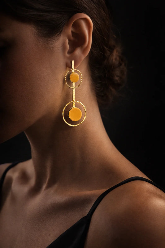 Gold-tone drop earrings on ear with orange round stones and halo ring details