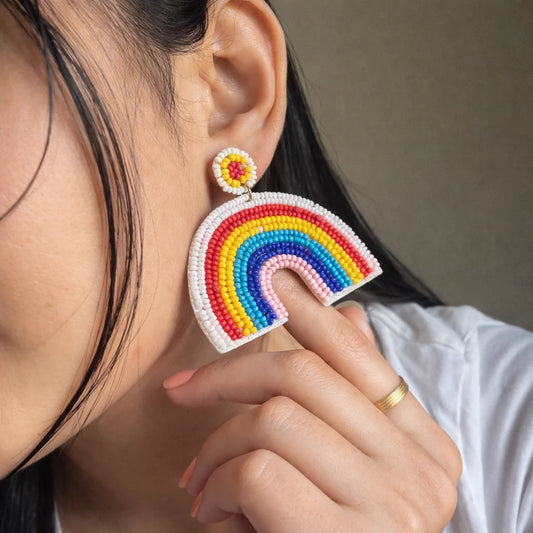 Rainbow beaded earrings worn on ear, large rainbow arc drops with bead stud backs.