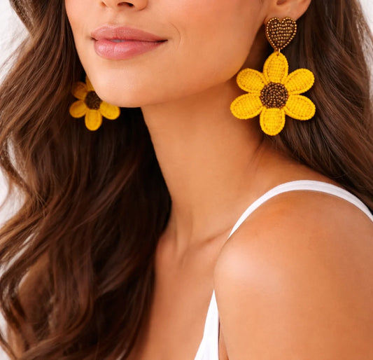 Yellow beaded sunflower drop earrings with dark heart-shaped stud tops on model
