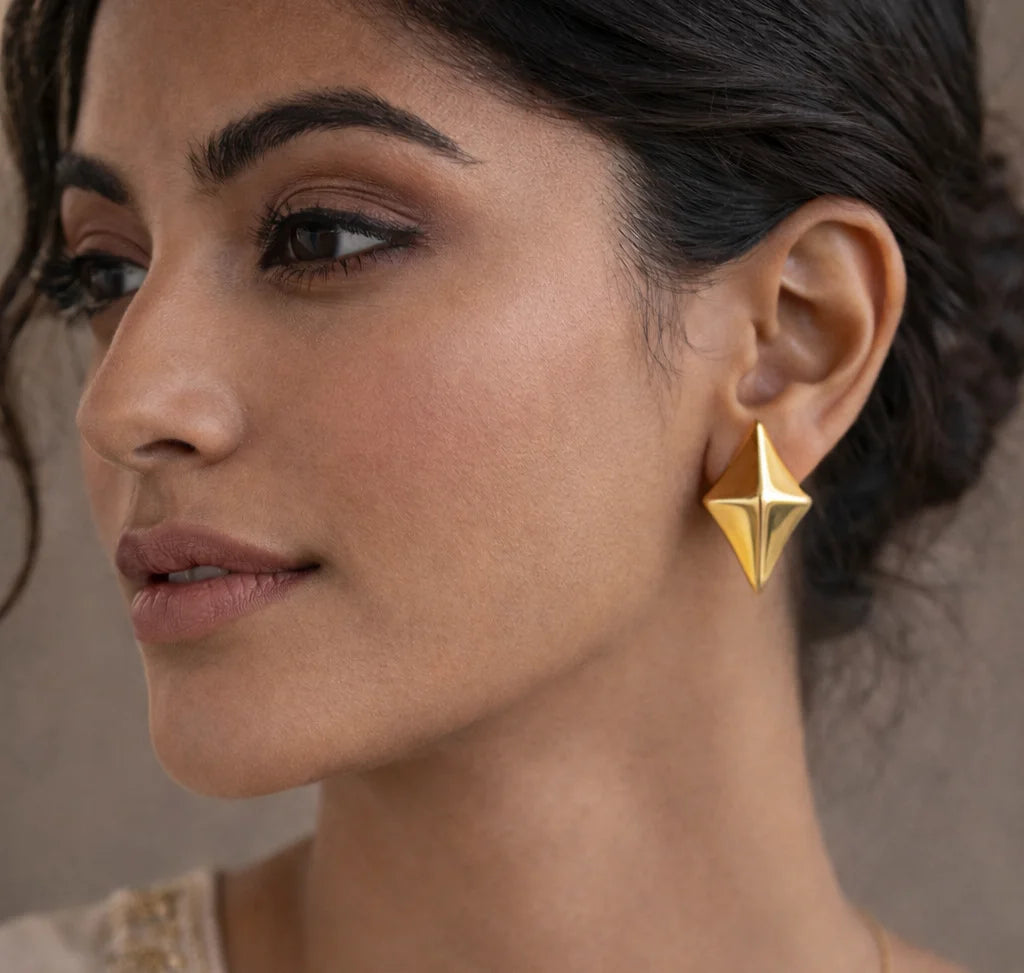 Gold-tone faceted rhombus star stud earring on ear