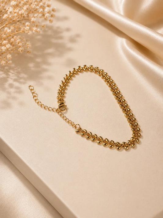 Gold-tone oval link bracelet, coiled on a light fabric surface