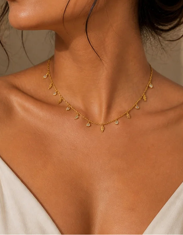 Gold-plated feather charm necklace and small feather stud earrings on model