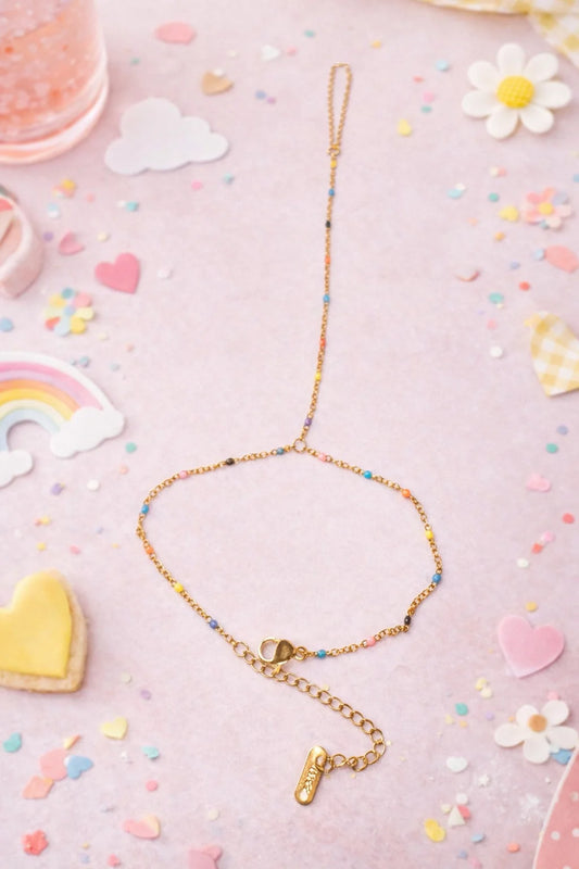 Dainty color hand chain with gold-tone links and small vertical charm, blue bead accents