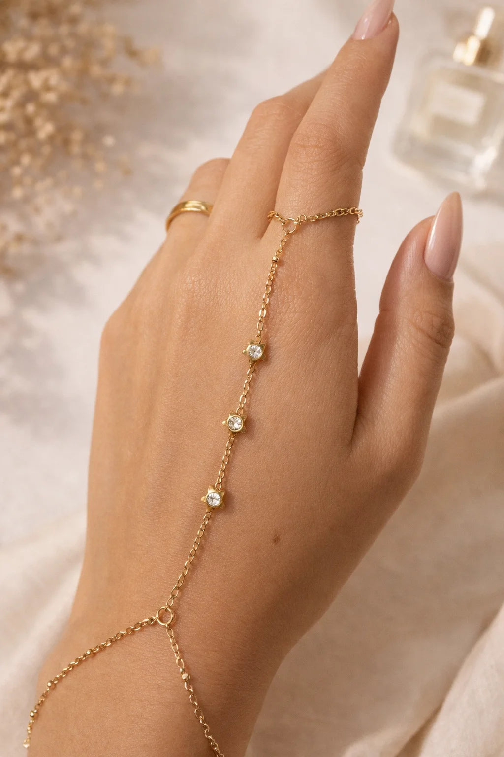 Gold-tone hand chain with five small crystal star charms worn on finger