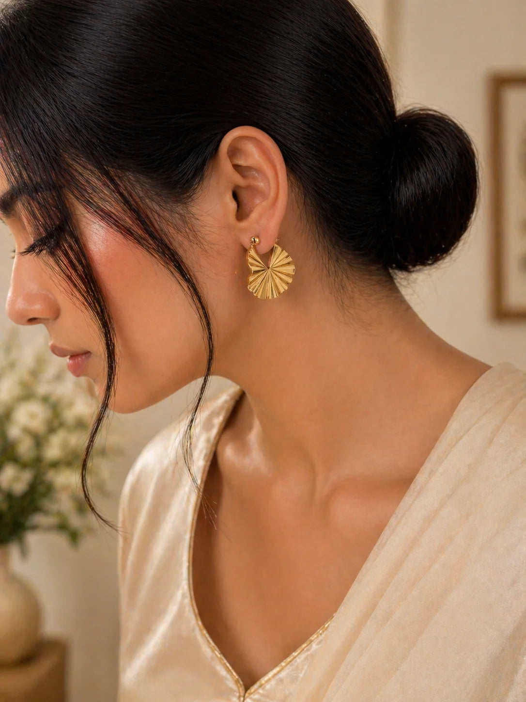 Gold-plated heart hoop earrings on model ear, ridged geometric face