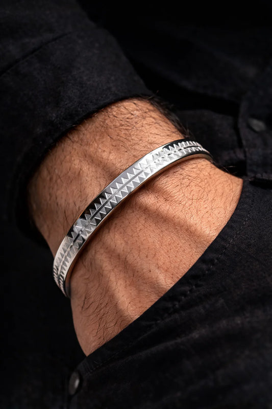 Stainless steel men's kada bracelet worn on wrist, triangular pattern along the edge