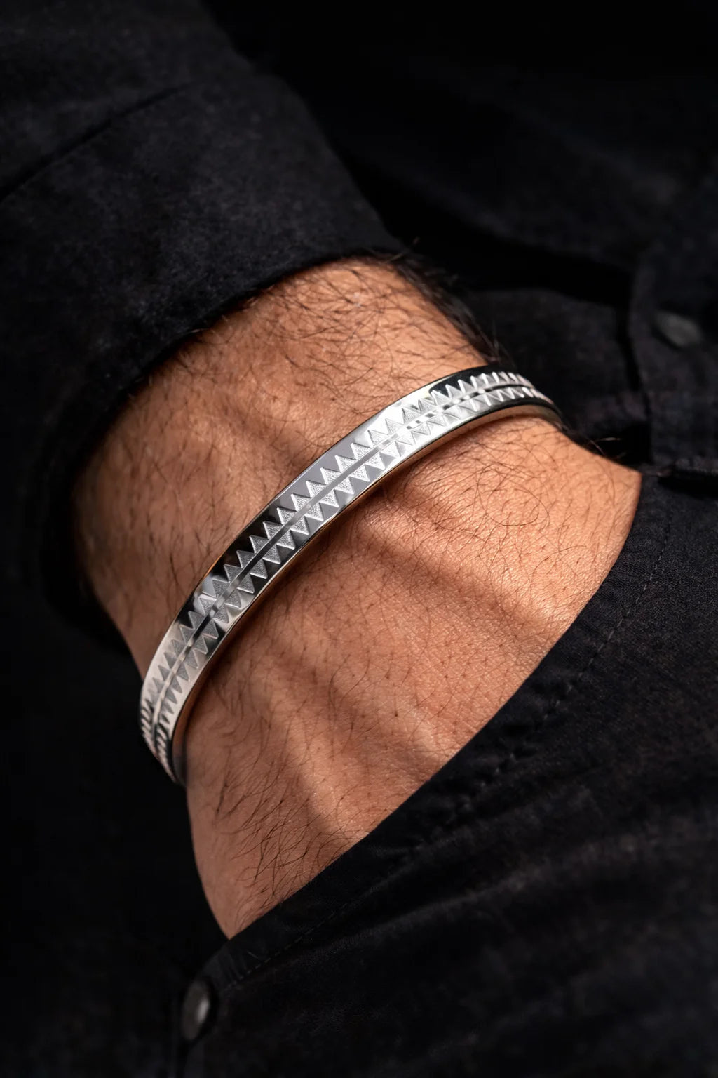 Stainless steel men's kada bracelet worn on wrist, triangular pattern along the edge