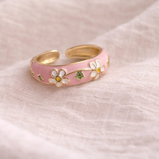 Enamel ring with pink band, white flower inlays, and gold-tone rim