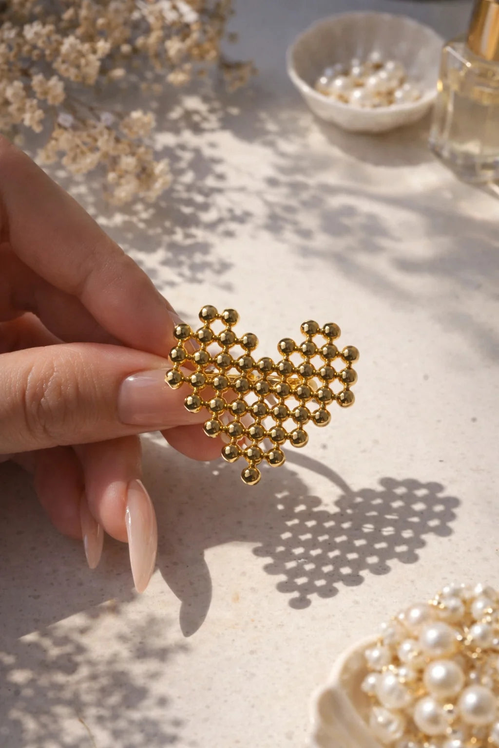 Gold honeycomb heart ring with small beaded lattice links, held on a finger.