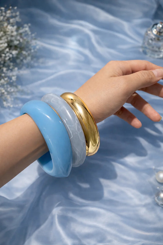 Translucent blue resin kada bangle with gold-tone inner rim on hand