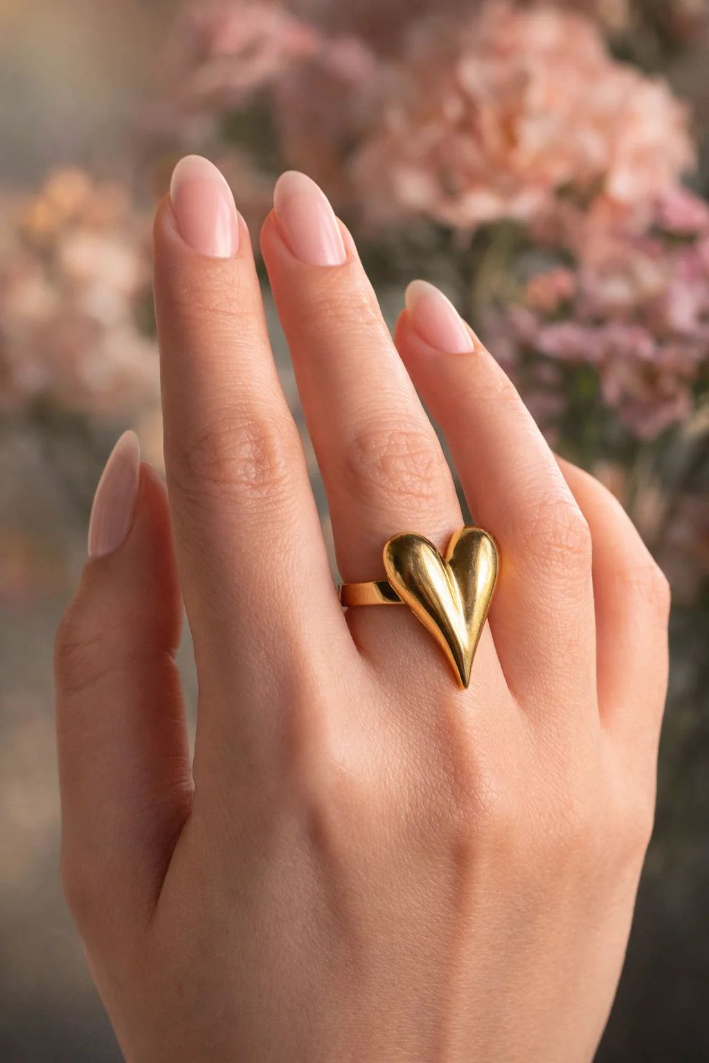 Gold tone heart pop ring worn on finger, glossy curved heart design