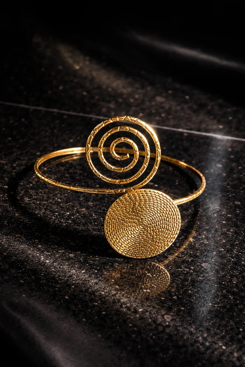 Gold spiral arm cuff with two disc charms and coiled swirl detail