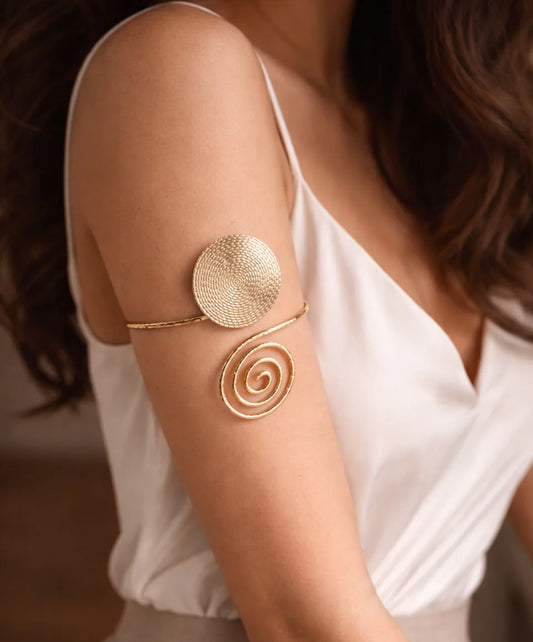 Gold spiral arm cuff on wrist with round disc and lower swirl disc
