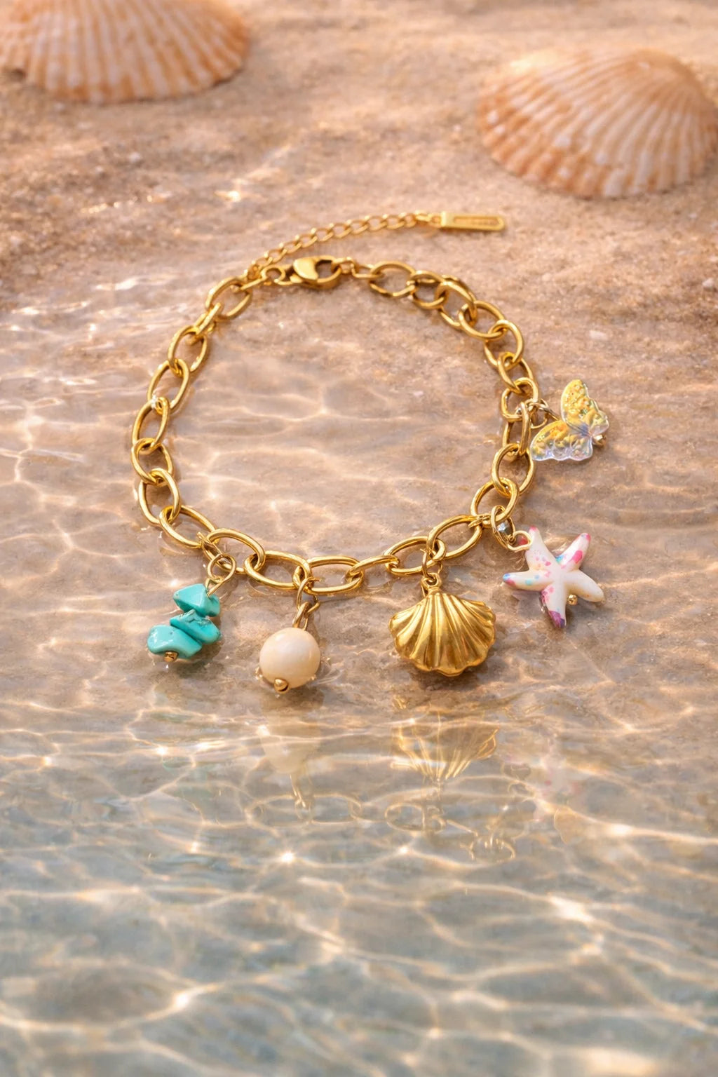 Gold-tone charm bracelet with seashell, starfish, pearl bead, teal charm, and link chain