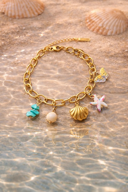 Gold-tone charm bracelet with seashell, starfish, pearl bead, teal charm, and link chain