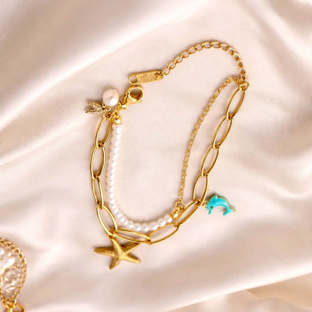 Gold charm bracelet with pearl beads, starfish and turquoise dolphin charms, clasp end