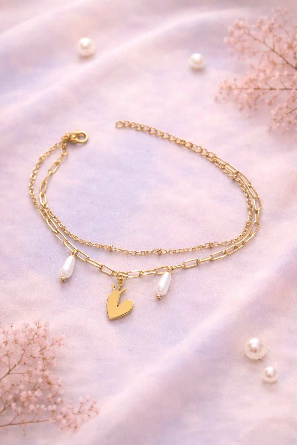 Gold-tone charm bracelet with heart charm, crown charm, and pearl drops