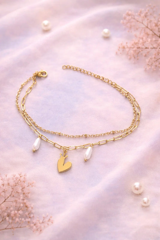 Gold-tone charm bracelet with heart charm, crown charm, and pearl drops