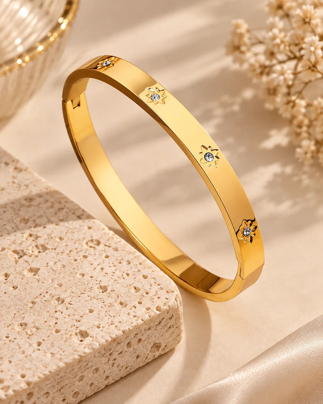 Gold kada bangle bracelet with tiny star-like gems along the band, angled view.