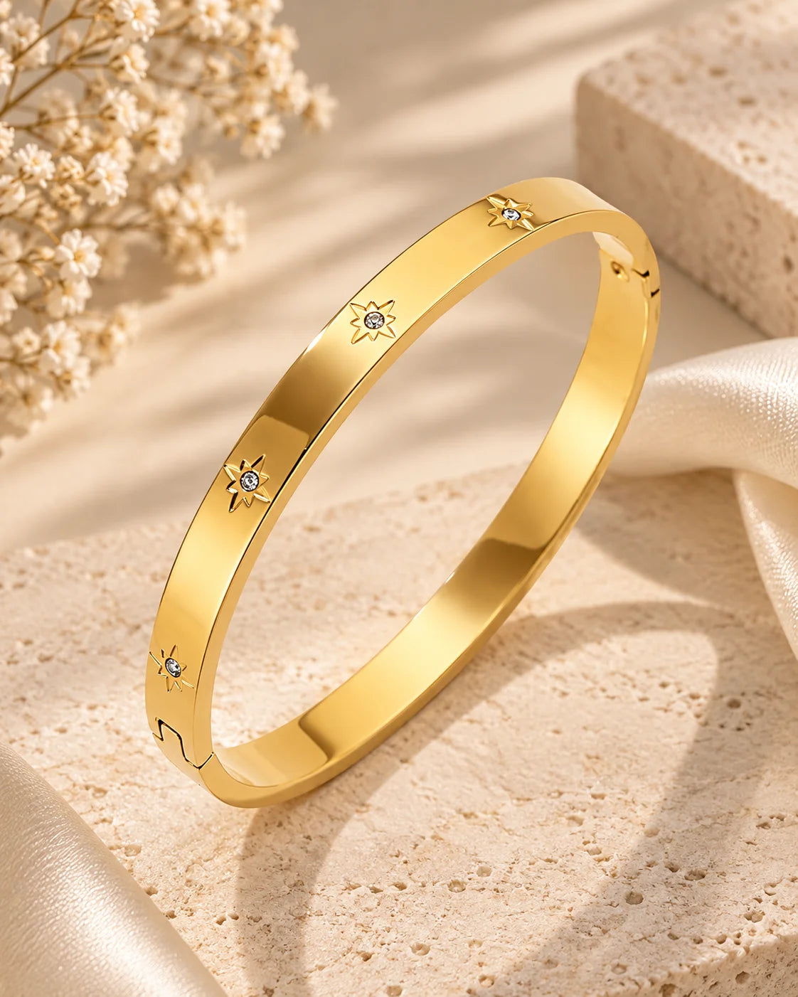 Gold kada bangle bracelet with evenly spaced star-like gem motifs on the front face.