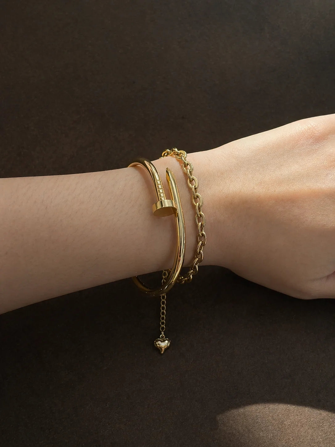 Gold chain bracelet with heart drop charm, worn on wrist
