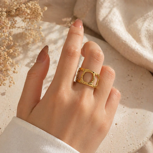 Gold square bezel ring with orange center, ornate raised frame