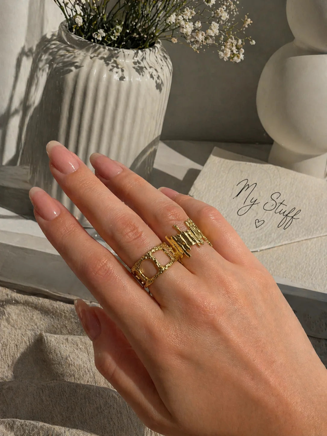 Gold ring with stacked square cutout design, worn on finger