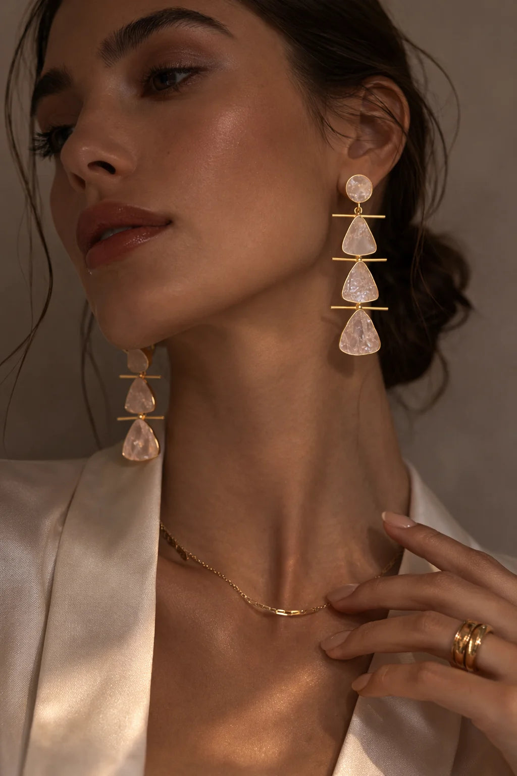 Model wearing gold and raw rose quartz cascade earrings with three dangling teardrops