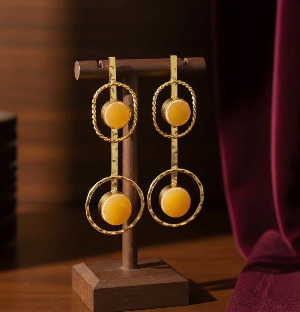 Gold-tone drop earrings on a stand with orange round halo stones and linked rings