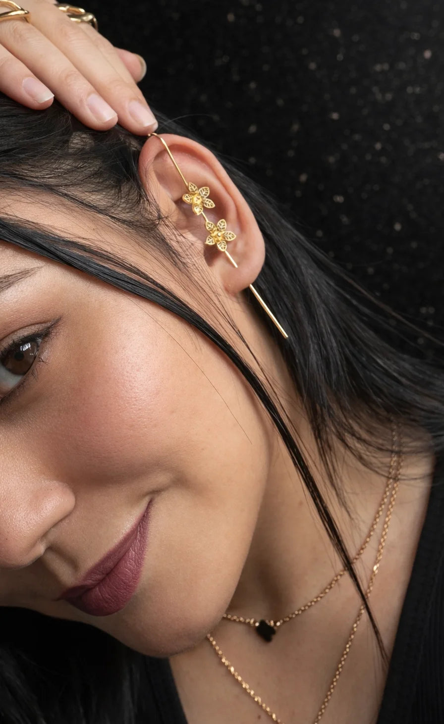 Gold-tone floral ear cuff on ear with small dangling flower details