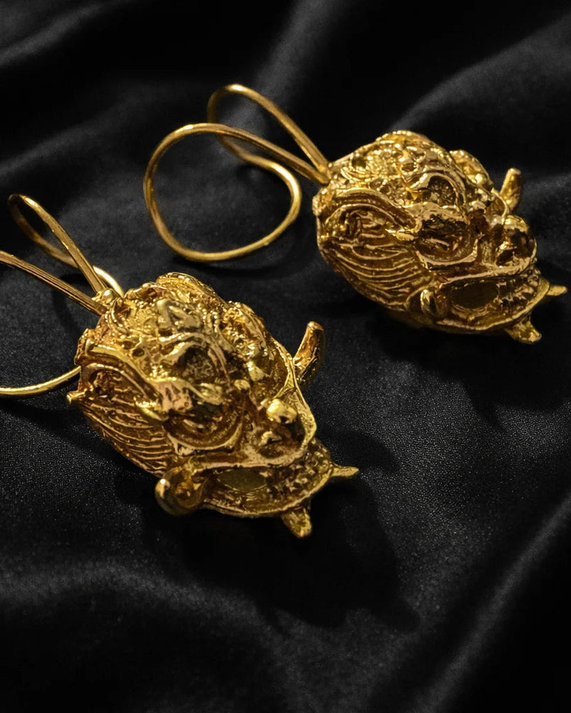 Gold-tone demon face ear cuffs, close-up pair with curved hoops