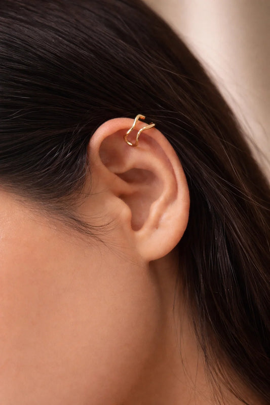 Gold wavy ear cuff worn on ear, single open loop with curved bar