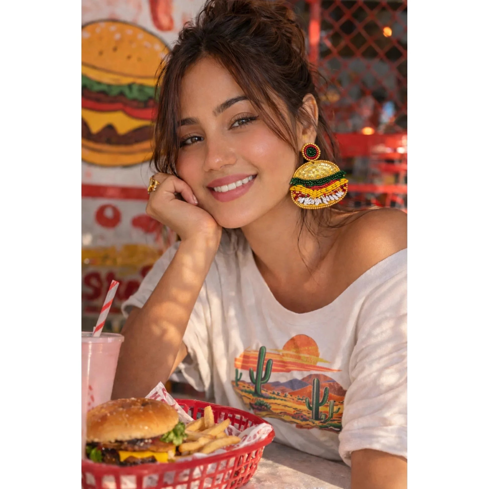 Beaded burger earrings on model: gold bun, green lettuce, red stripe, round green center