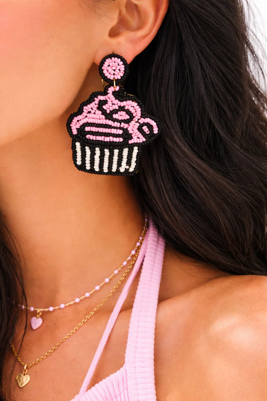Beaded cupcake dangle earrings with pink frosting and black cupcake base, on ear