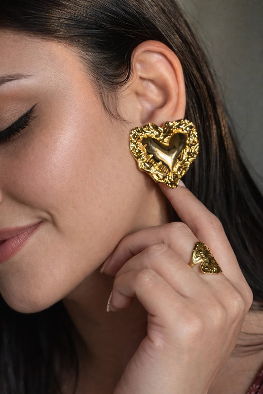 Heart stud earrings with textured gold-tone finish and heart cutout, worn on ear