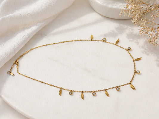 Gold-plated feather charm necklace with small leaf drops and pearl bead accents