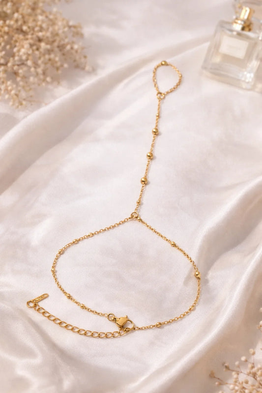 Gold hand chain bracelet with small bead links and small charm, open loop design