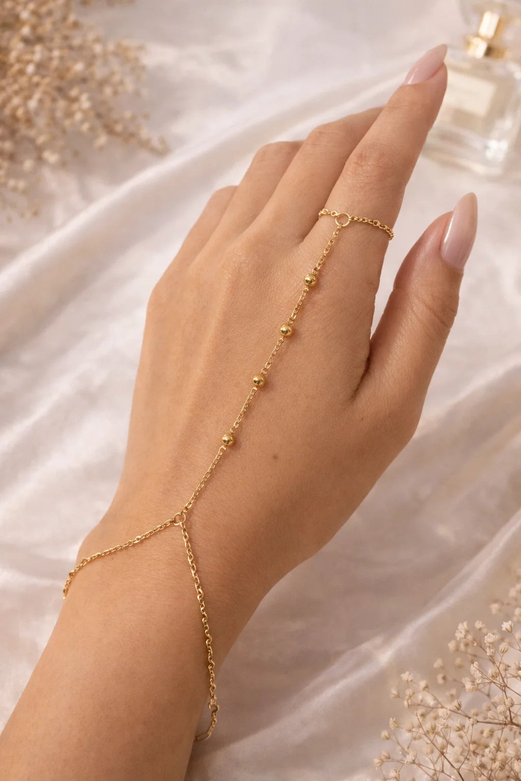 Gold hand chain worn on hand, long beaded links with small charm