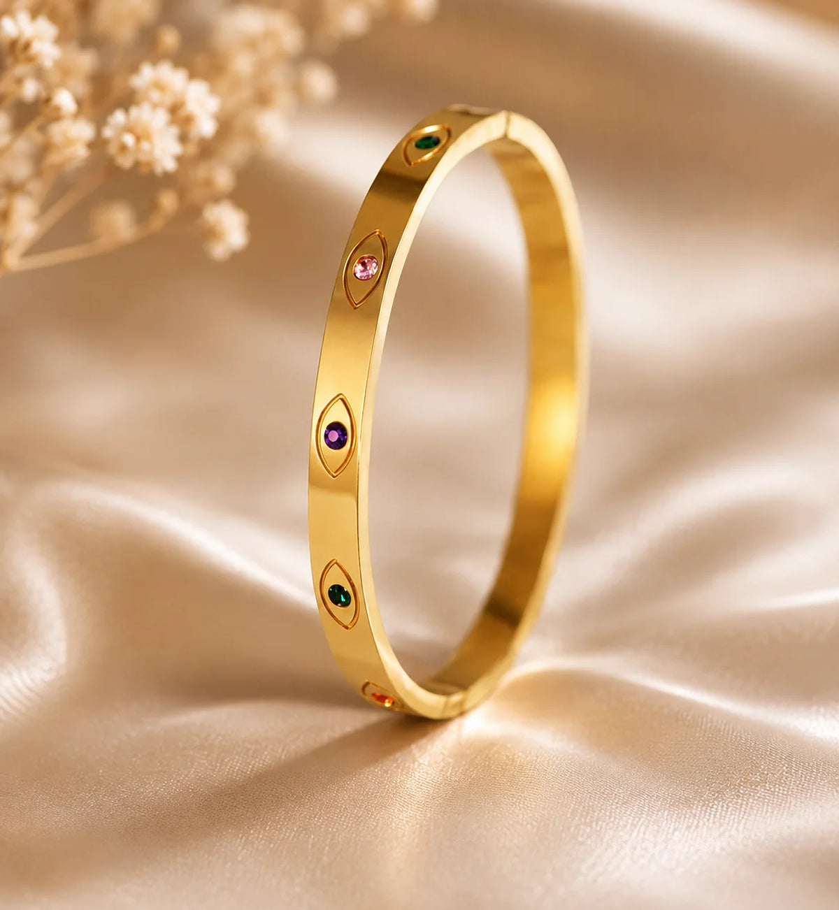 Gold-tone bangle bracelet with colored eye-shaped stones, infinity kada style