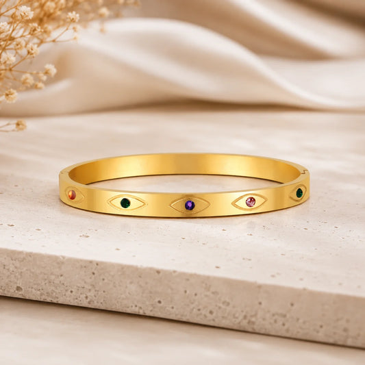 Gold-tone open bangle with inset eye stones in green, purple, and red