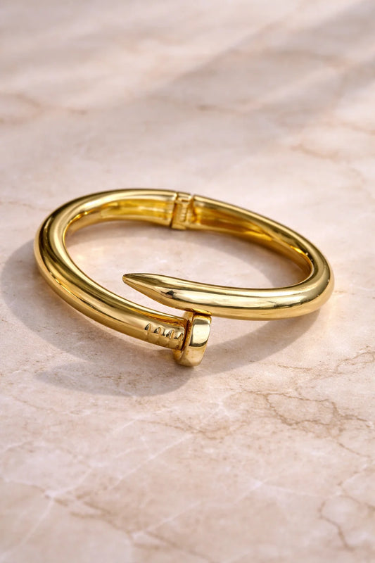 Gold-tone chunky bangle with raised nail-like studs and hinged clasp