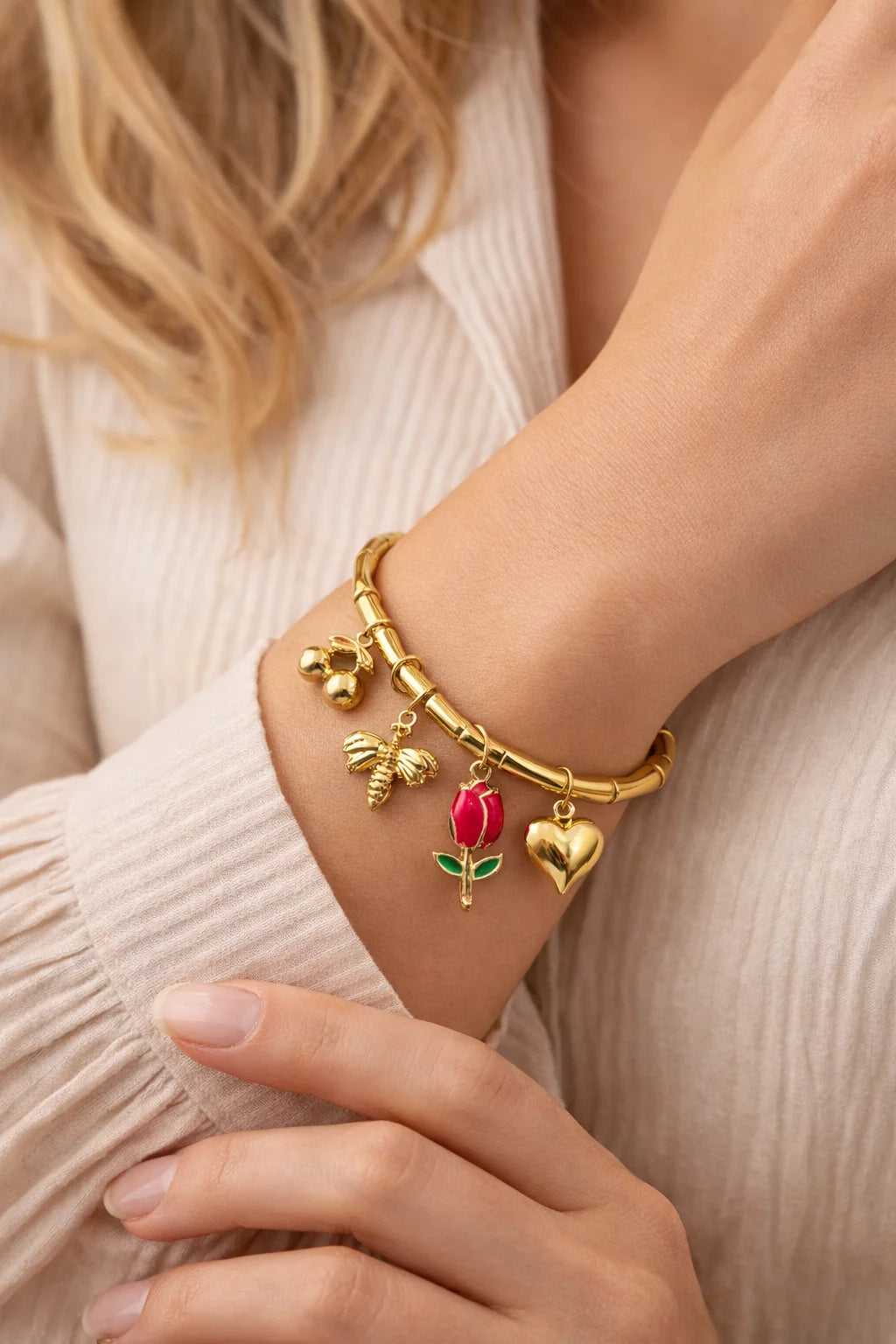 Gold kada bracelet close-up with red tulip and heart charms on wrist