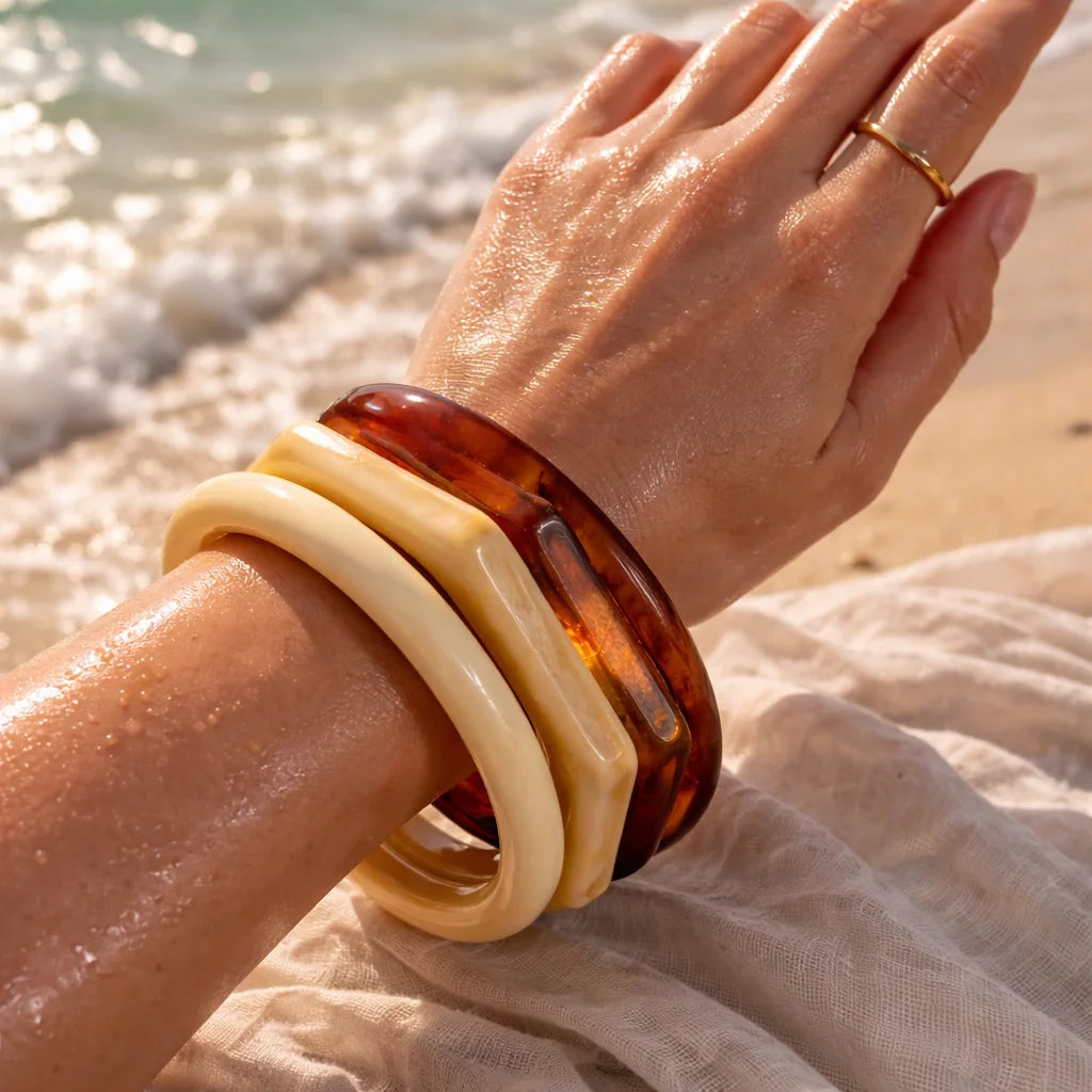 Stacked cream and amber resin bangles on wrist with glossy tortoiseshell detail