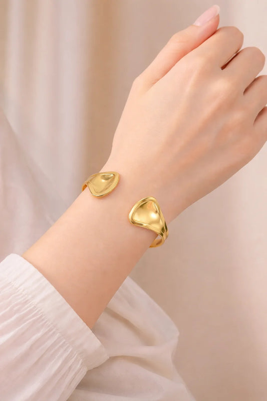 Gold kada bangle on wrist with two rounded, sculpted end plates