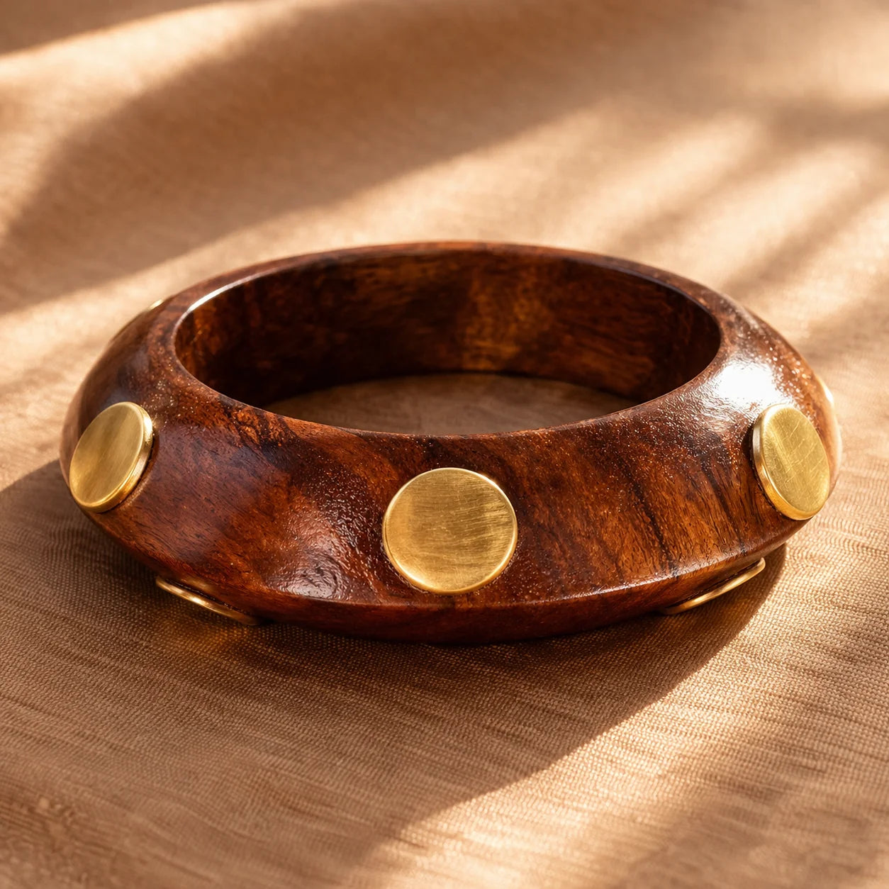 Brown wooden bangle with gold round studs and an open inner curve