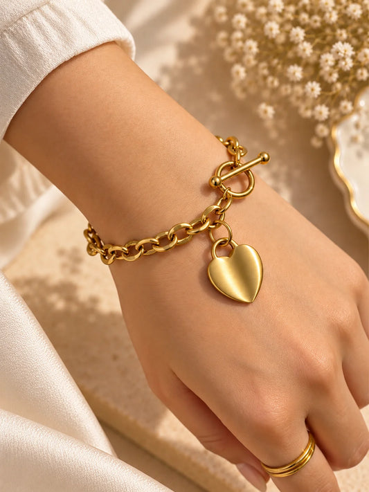 Gold tone chunky chain bracelet with heart pendant and toggle clasp, worn