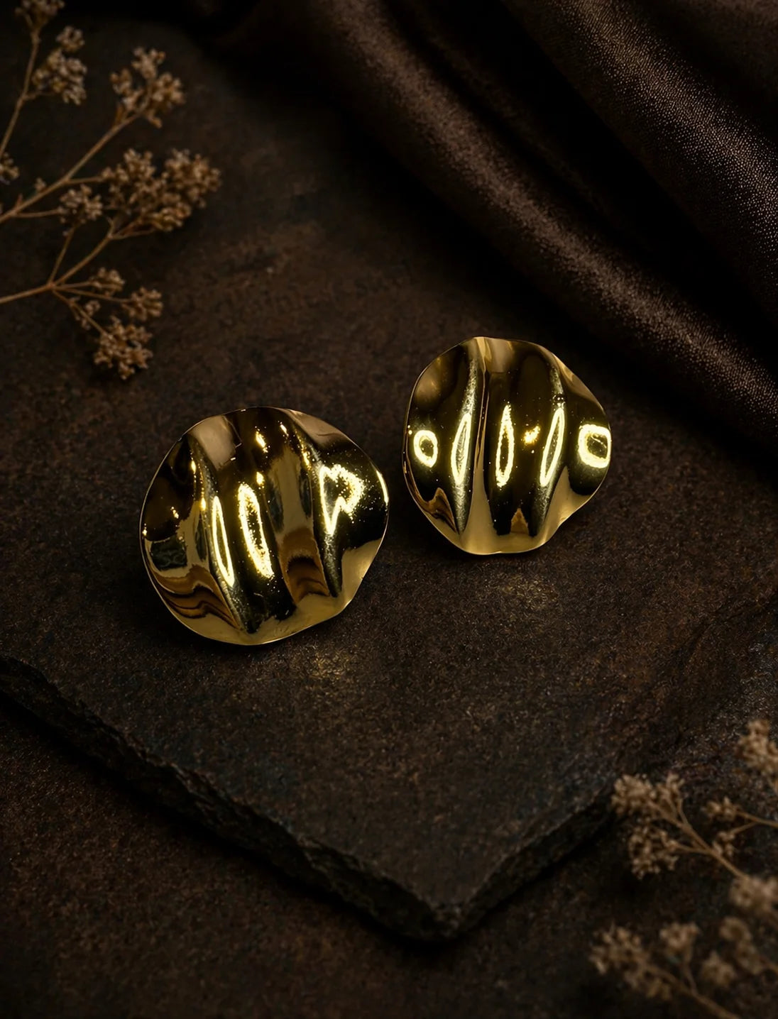 Gold-plated wave texture stud earrings on dark fabric, pair of round studs