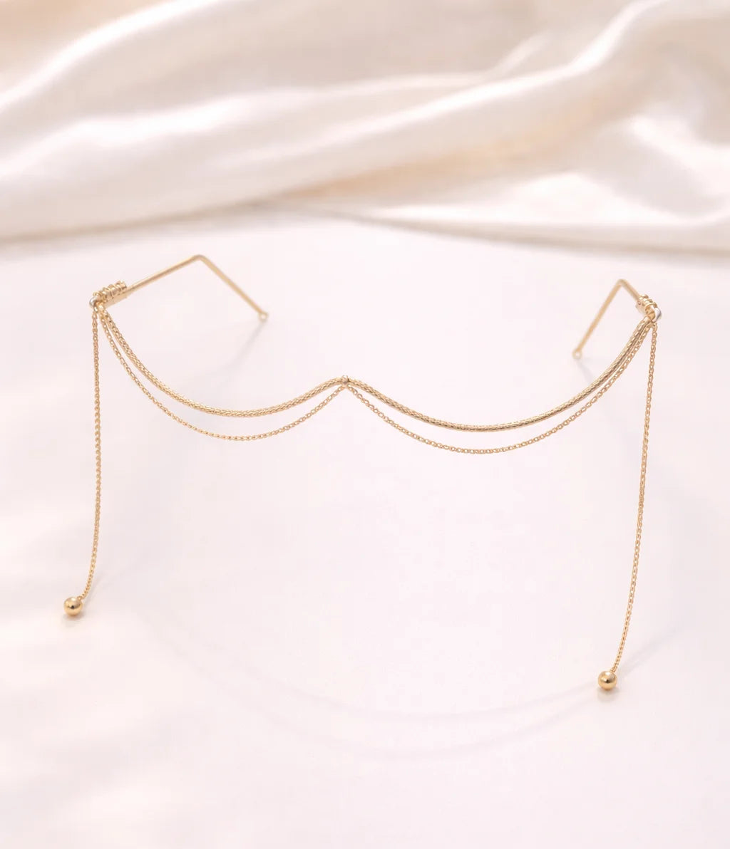 Gold-tone draped chain facelet with two dangling ball ends and curved central drape