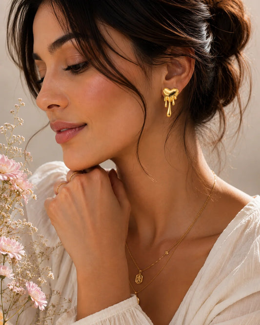 Gold melting heart earrings with drip design, worn on ear